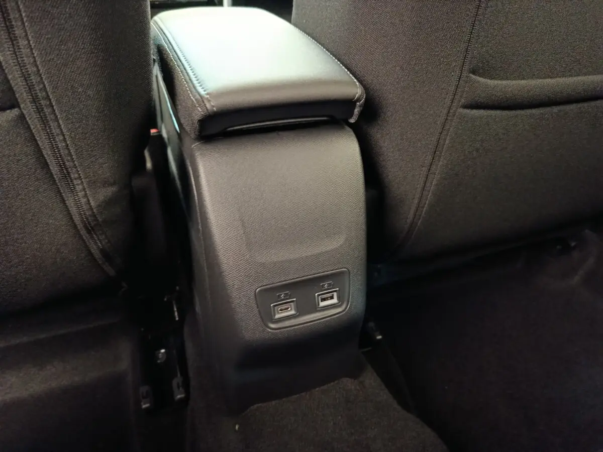 Vue rapprochée de la console centrale arrière noire avec ports USB dans une Peugeot 208 électrique blanche 2024.