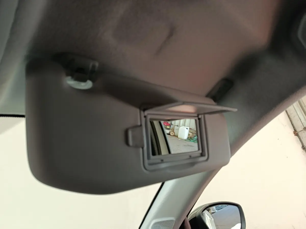 Miroir de courtoisie ouvert sur pare-soleil côté conducteur dans l’habitacle d’une Peugeot 208 électrique blanche.