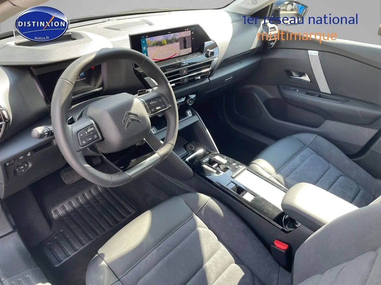 Intérieur moderne de la Citroën C4 2024, vue côté conducteur, sièges cuir noir et écran tactile avec caméra de recul.