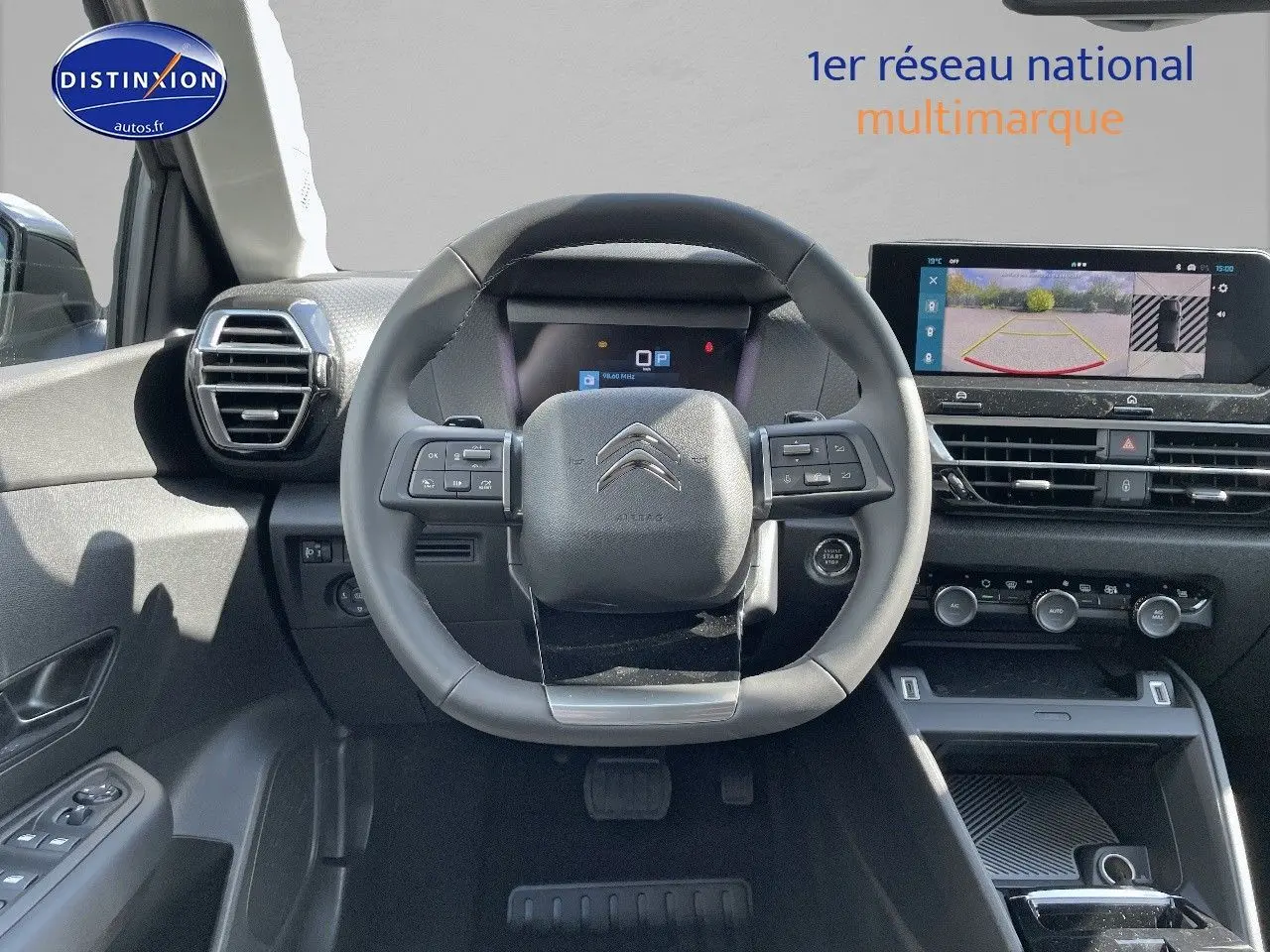 Vue frontale du poste de conduite de la Citroën C4 2024, avec volant compact et écran tactile affichant la caméra de recul.