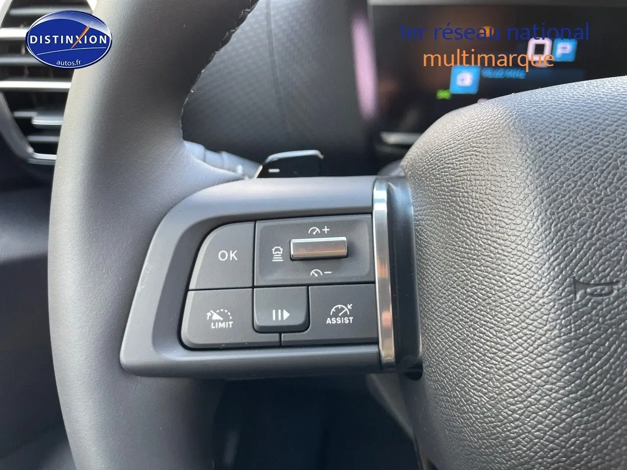 Gros plan sur les commandes au volant à gauche du Citroën C4 gris platinium 2024, boutons de régulateur et assistant de conduite.