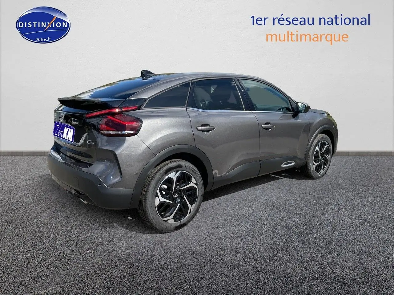 Vue 3/4 arrière droite d'une Citroën C4 2024 gris platinium métal avec jantes noires et toit noir contrasté.