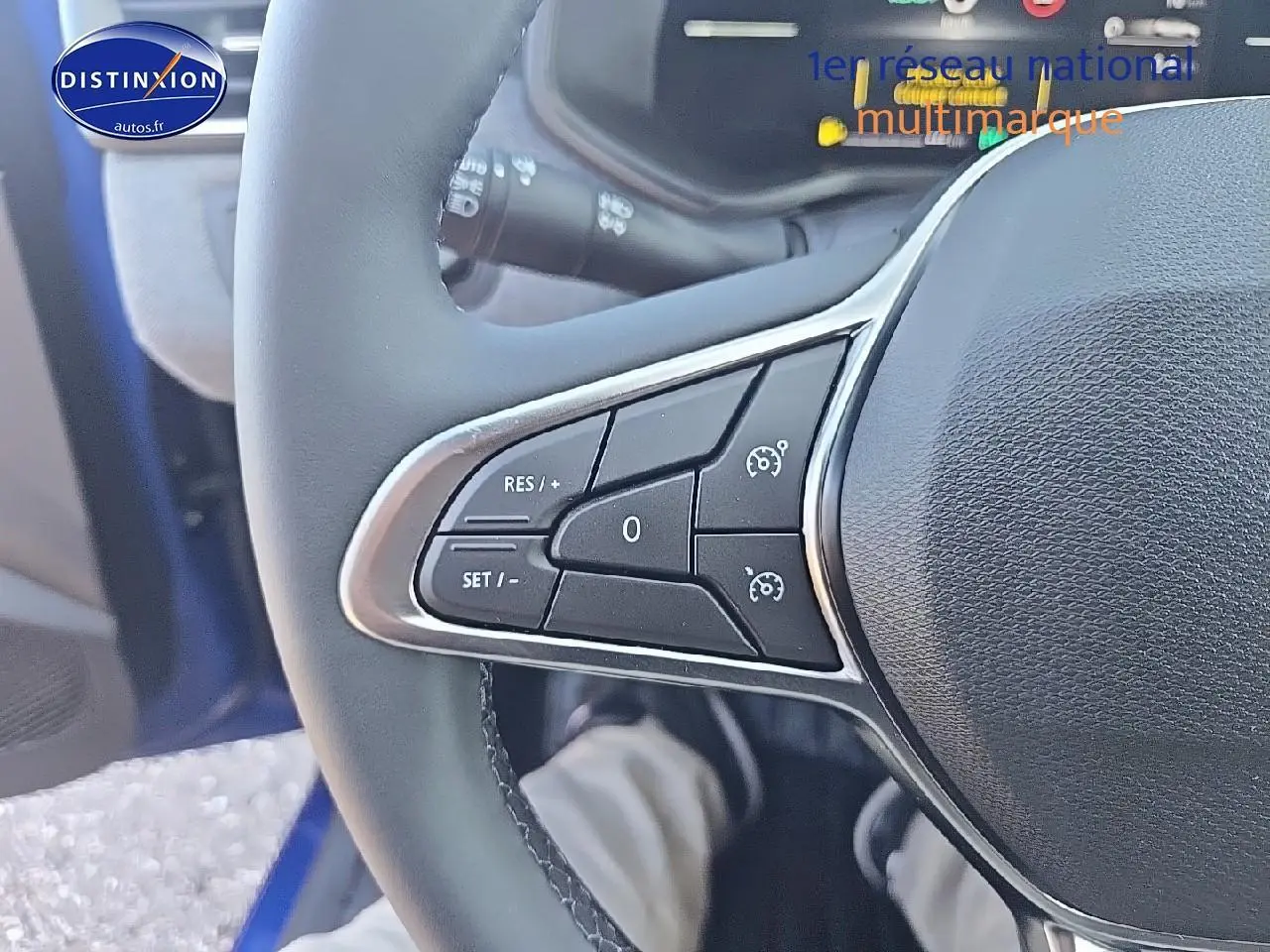 Gros plan sur les commandes au volant côté gauche d’une Renault Clio V Bleu Iron 2025 hybride essence.