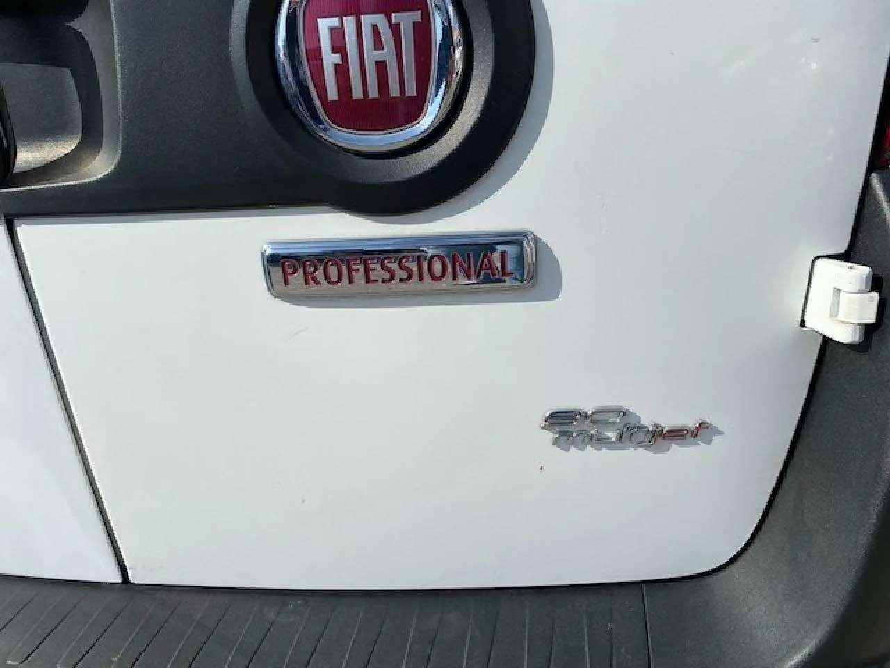 Gros plan sur la porte arrière blanche d'un FIAT Doblo 1.3 Multijet avec badges Professional et 90 Multijet.