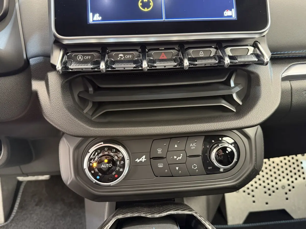 Vue rapprochée du tableau de bord de l'Alpine A110 Légende 2019, mettant en valeur la console de climatisation noire avec commandes circulaires.
