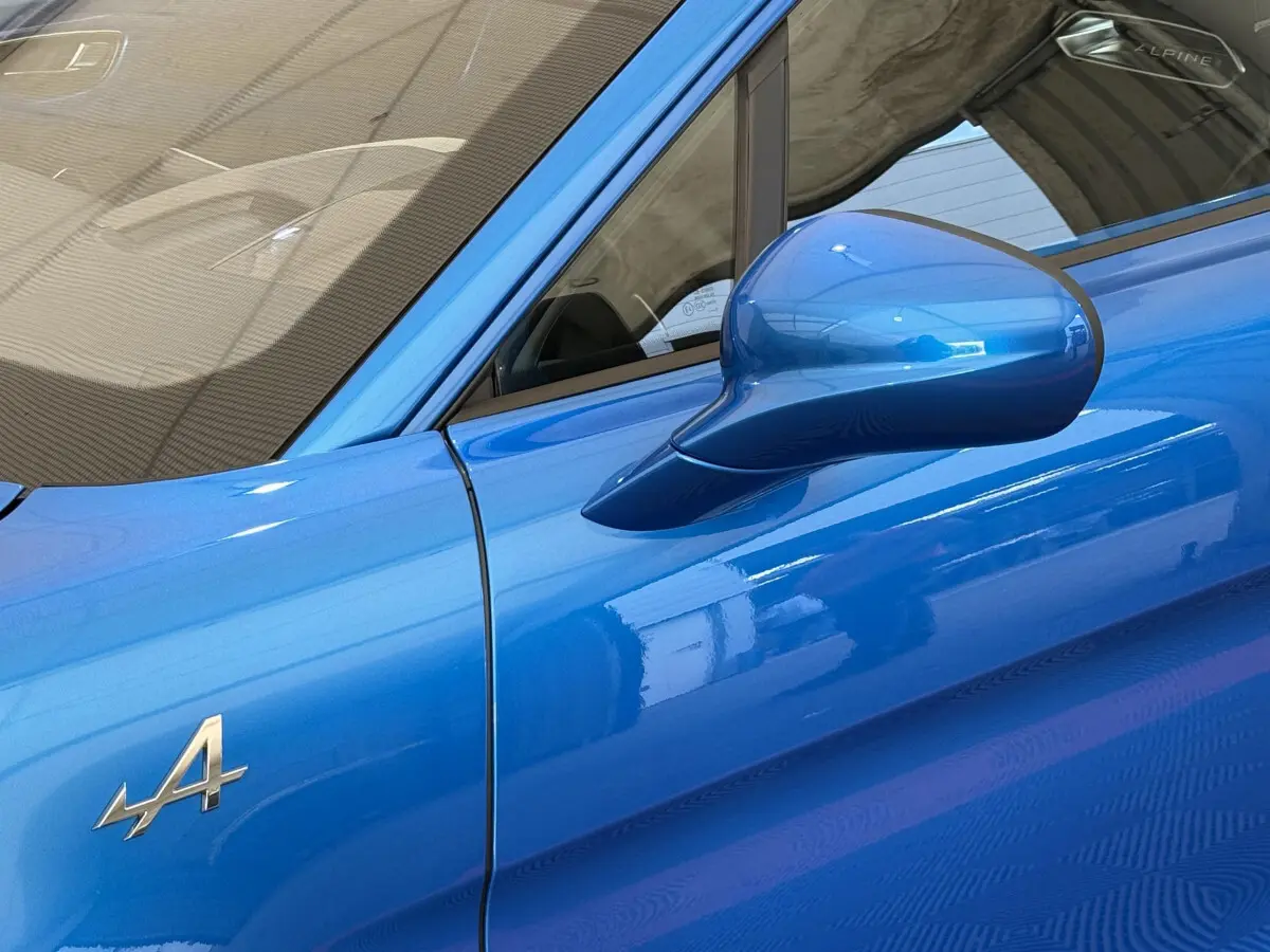 Détail du rétroviseur côté gauche et logo Alpine sur la portière d'une A110 Legende bleu 2019.