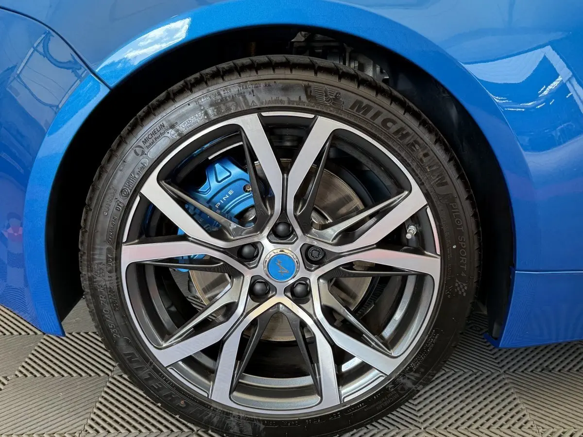 Gros plan sur la roue avant droite bleue d'une Alpine A110 Legende 2019, avec étrier de frein bleu et jante argentée.