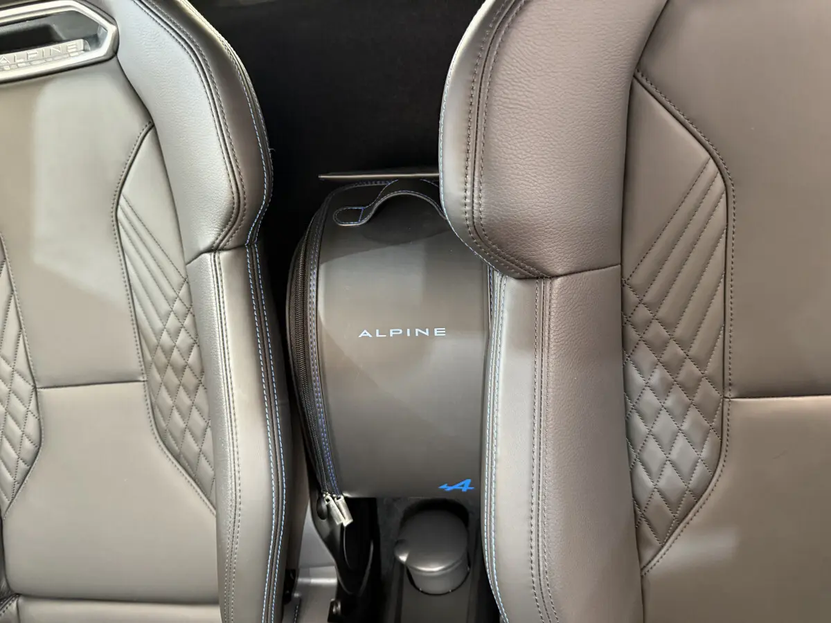 Gros plan sur la mallette Alpine bleue entre les sièges en cuir gris au design matelassé de l'A110 Legende 2019.
