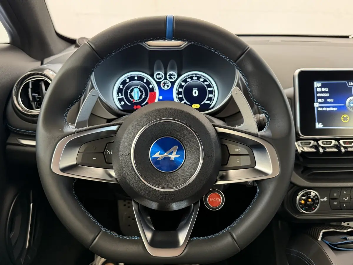 Vue frontale du volant cuir noir avec logo Alpine bleu et bouton rouge Sport sur le tableau de bord de l'Alpine A110 Legende 2019.