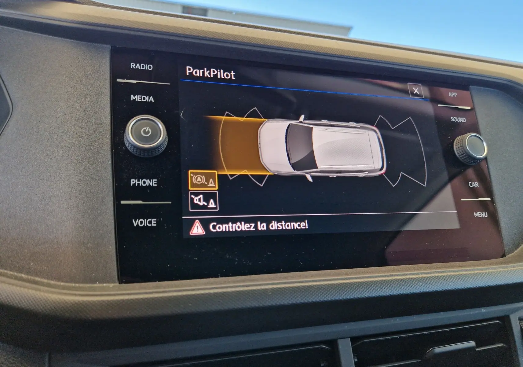 Écran central du Volkswagen T-Cross argent métal 2019 montrant l'alerte ParkPilot avec contrôle de distance actif.