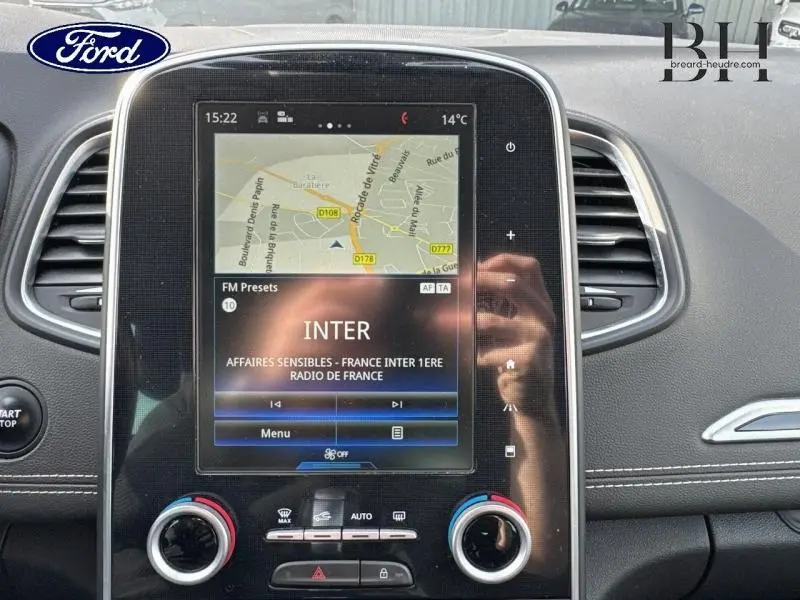 Écran tactile central avec GPS et radio dans l'habitacle d'un Renault Grand Scenic noir étoilé, vue de face.