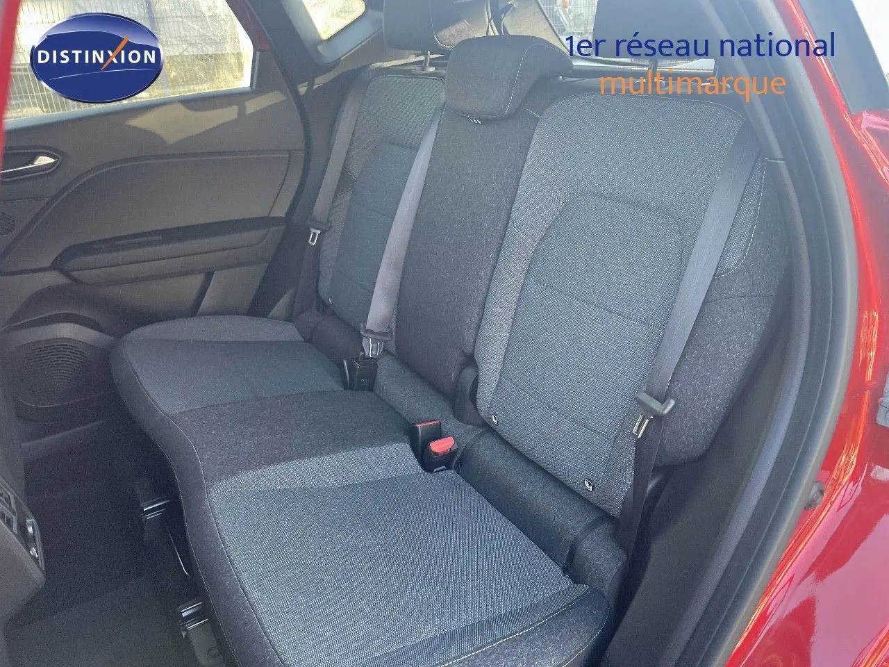 Vue intérieure sur les sièges arrière gris foncé du Renault Captur E-Tech Hybrid 2025, porte arrière rouge passion ouverte.