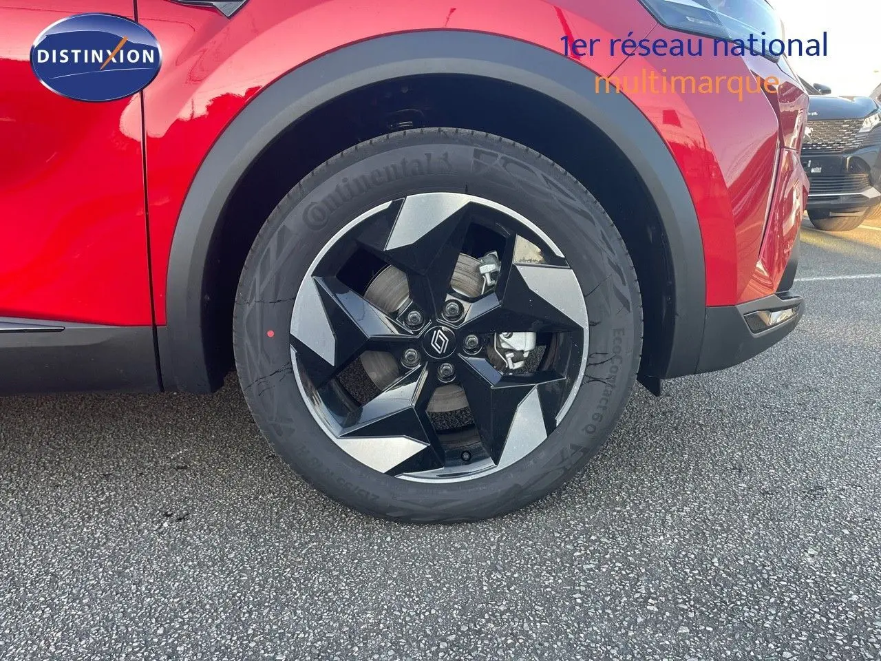 Gros plan sur la roue avant gauche d’un Renault Captur rouge passion avec jante noire et argentée au design géométrique.