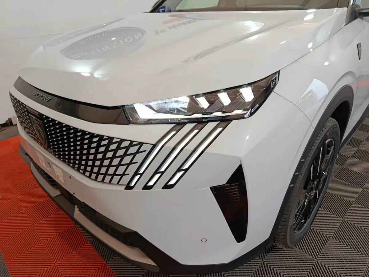 Vue 3/4 avant droit du Peugeot 3008 blanc hybride, mettant en valeur la calandre à motifs géométriques et les phares LED distinctifs.