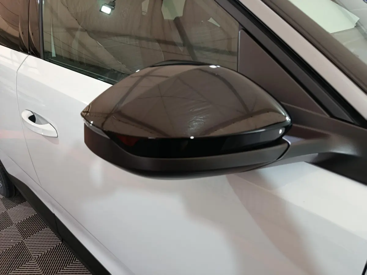 Gros plan sur le rétroviseur noir côté conducteur d’un Peugeot 3008 blanc, vue latérale gauche.