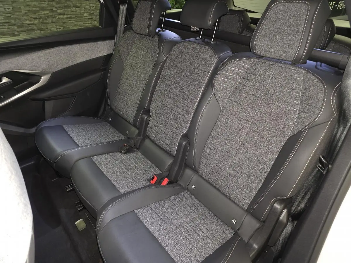Vue intérieure du siège arrière central en tissu gris et cuir noir du Peugeot 5008 hybride 2025, avec ceinture de sécurité visible.