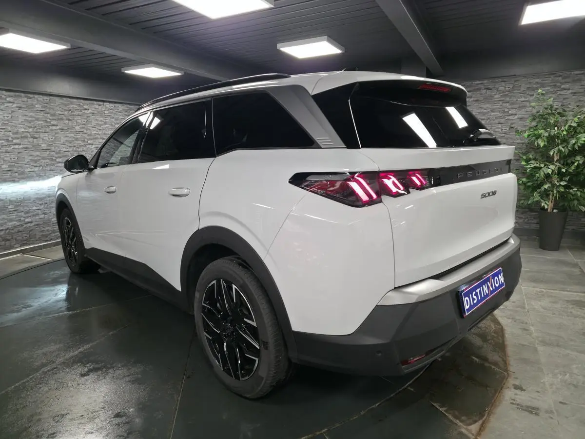 Vue 3/4 arrière droite du Peugeot 5008 blanc avec feux arrière LED à 3 griffes et jantes alliage noires.