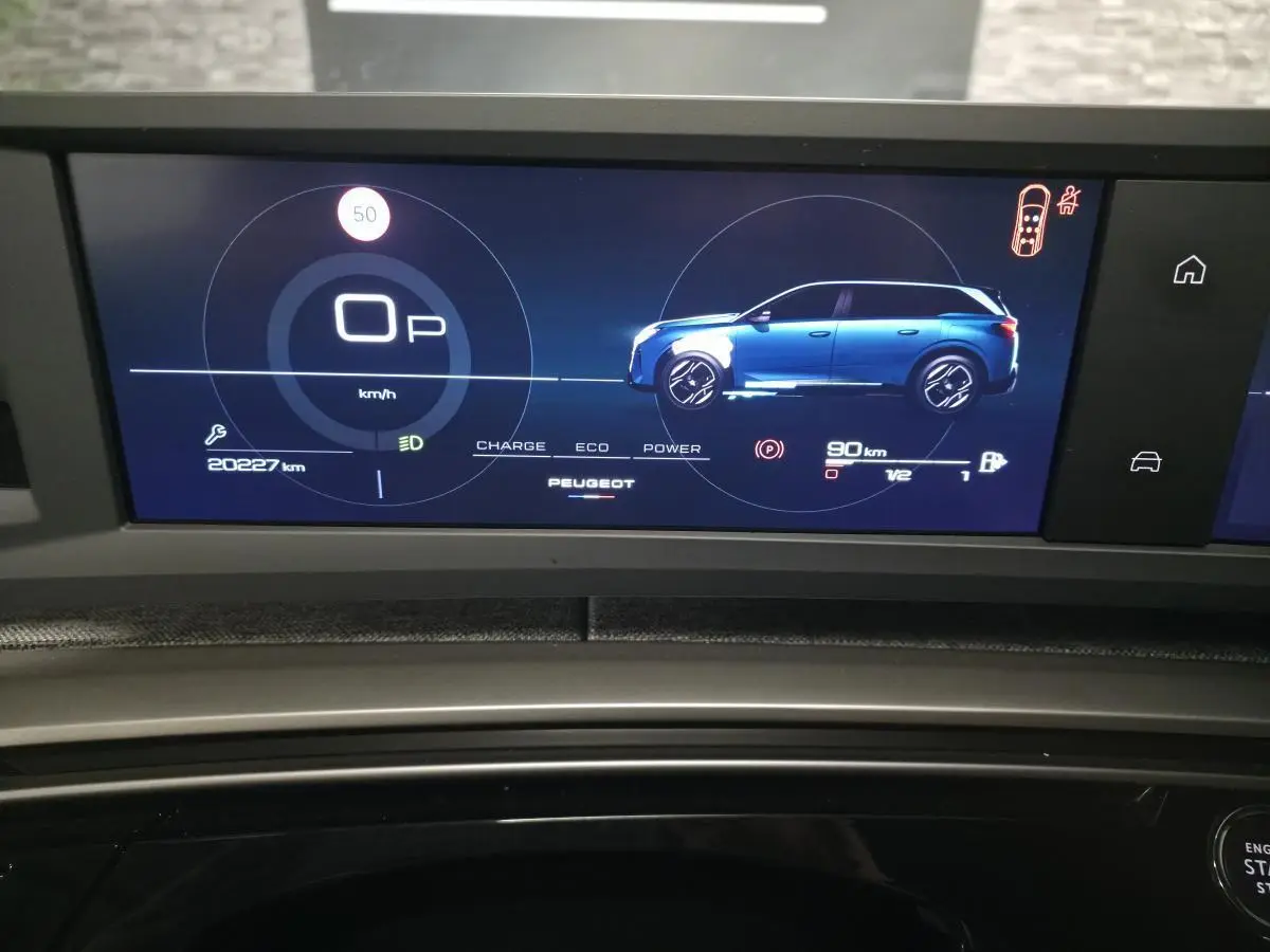 Affichage numérique du tableau de bord du Peugeot 5008 blanc, montrant la silhouette latérale droite du véhicule en mode hybride.