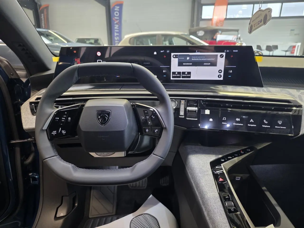 Vue intérieure centrée sur le volant compact cuir noir et l'écran panoramique du tableau de bord du Peugeot 3008 bleu.
