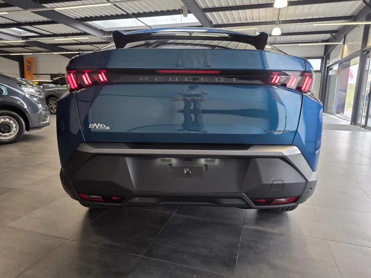 Vue arrière d’un Peugeot 3008 hybride bleu métallisé avec feux arrière LED à trois griffes et bandeau noir laqué.