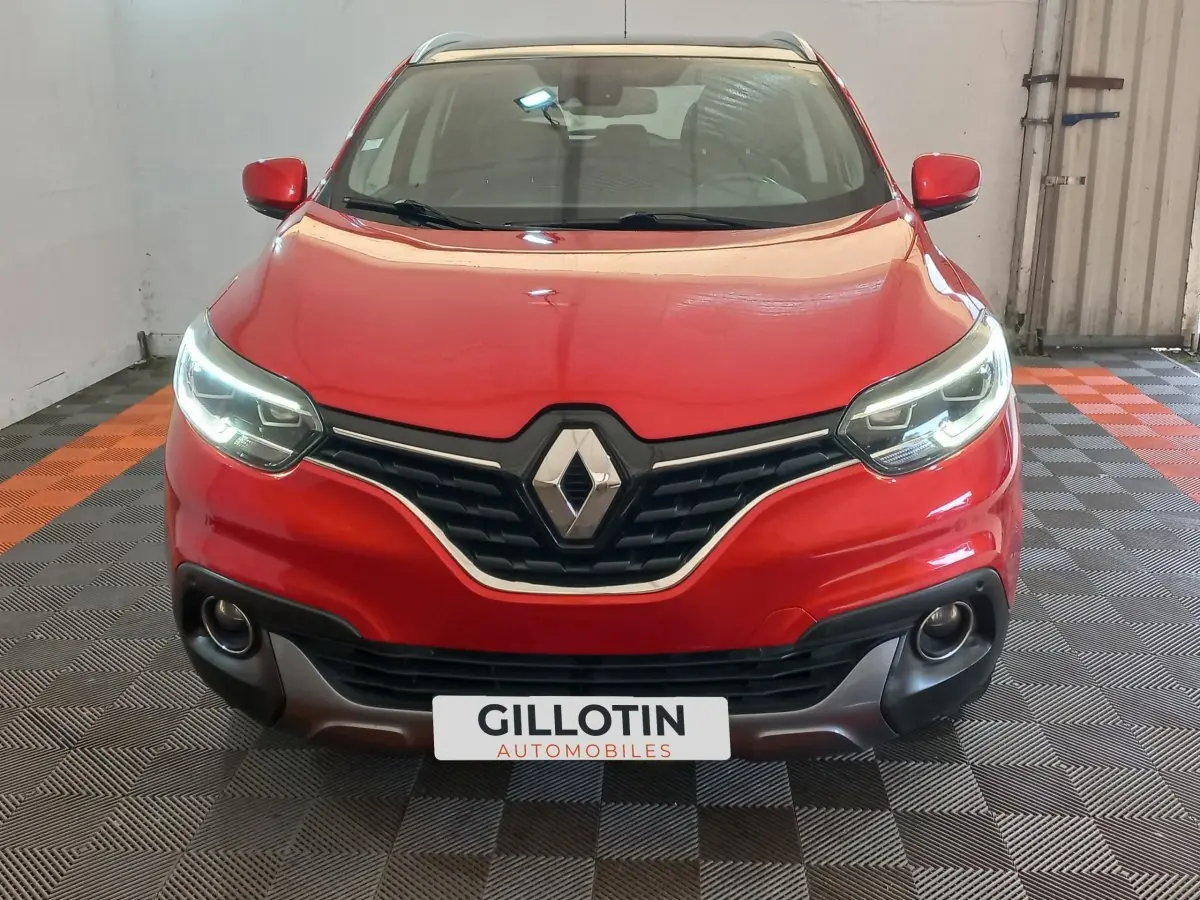 Vue avant d'un Renault Kadjar Intens Energy TCe 130 EDC rouge avec feux LED allumés dans un garage.