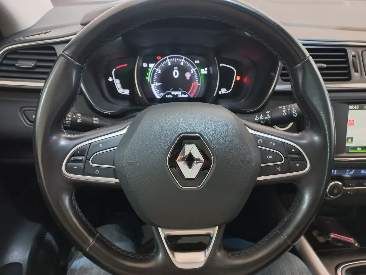 Vue intérieure centrée sur le volant cuir noir du Renault Kadjar Intens avec tableau de bord et écran tactile visible à droite.