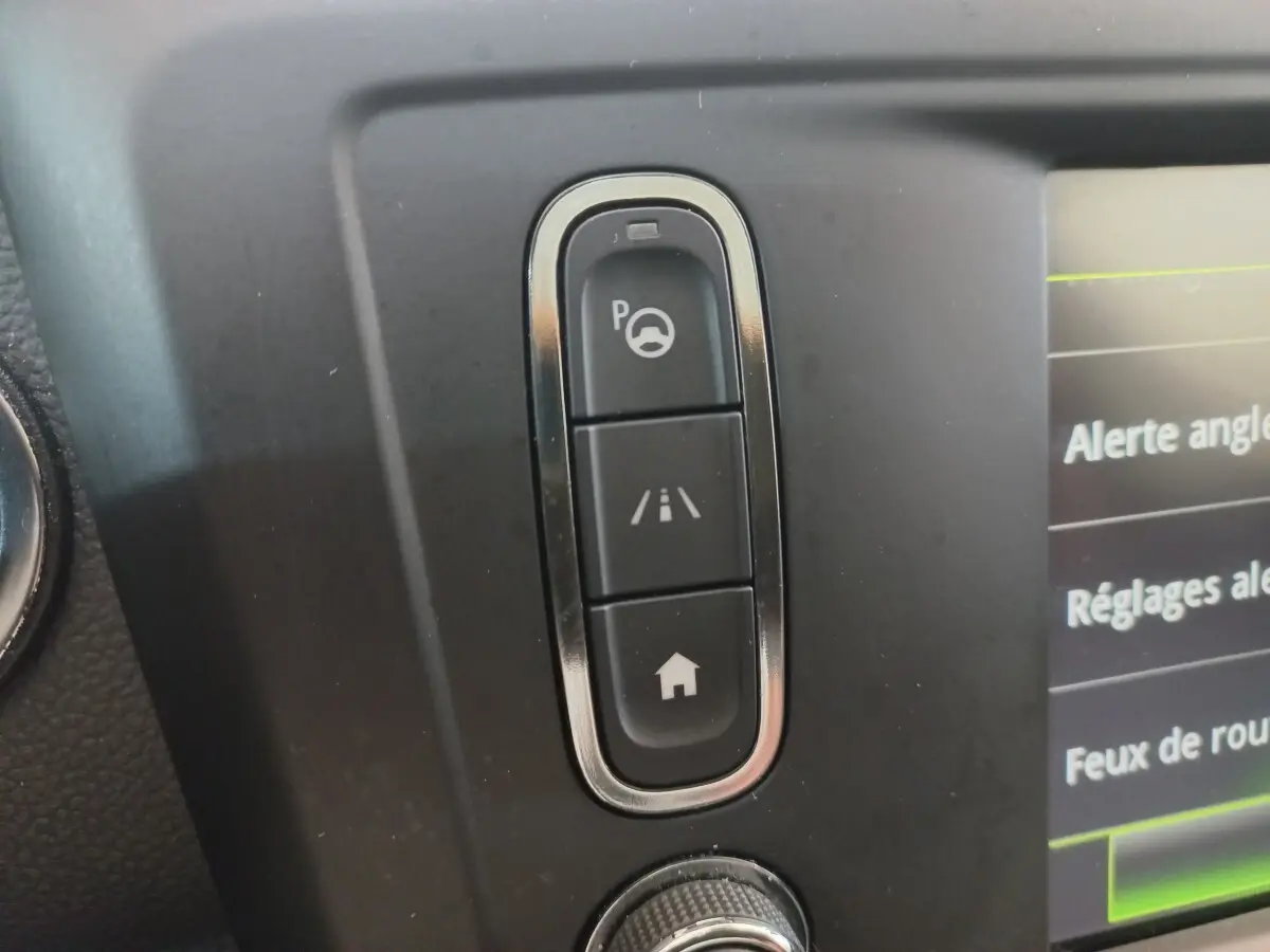 Gros plan sur les boutons de commande d’aide au stationnement et d’alerte de franchissement de ligne dans le tableau de bord Renault Kadjar Intens 2018.