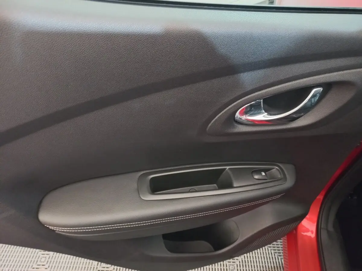 Détail de la porte intérieure côté conducteur du Renault Kadjar rouge, avec poignée chrome et bouton de verrouillage.