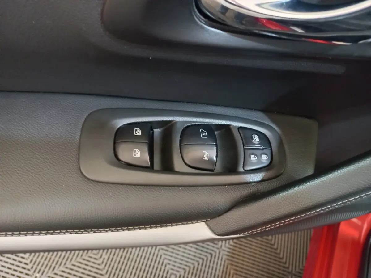 Gros plan sur les commandes de lève-vitres et verrouillage sur la porte côté conducteur d’un Renault Kadjar rouge.