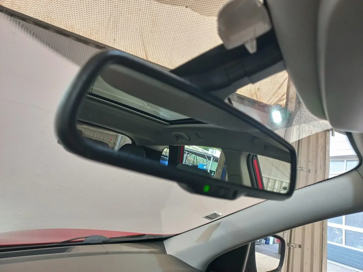 Rétroviseur intérieur d’un Renault Kadjar Intens rouge, avec toit ouvrant et partie de l’habitacle visible en reflet.