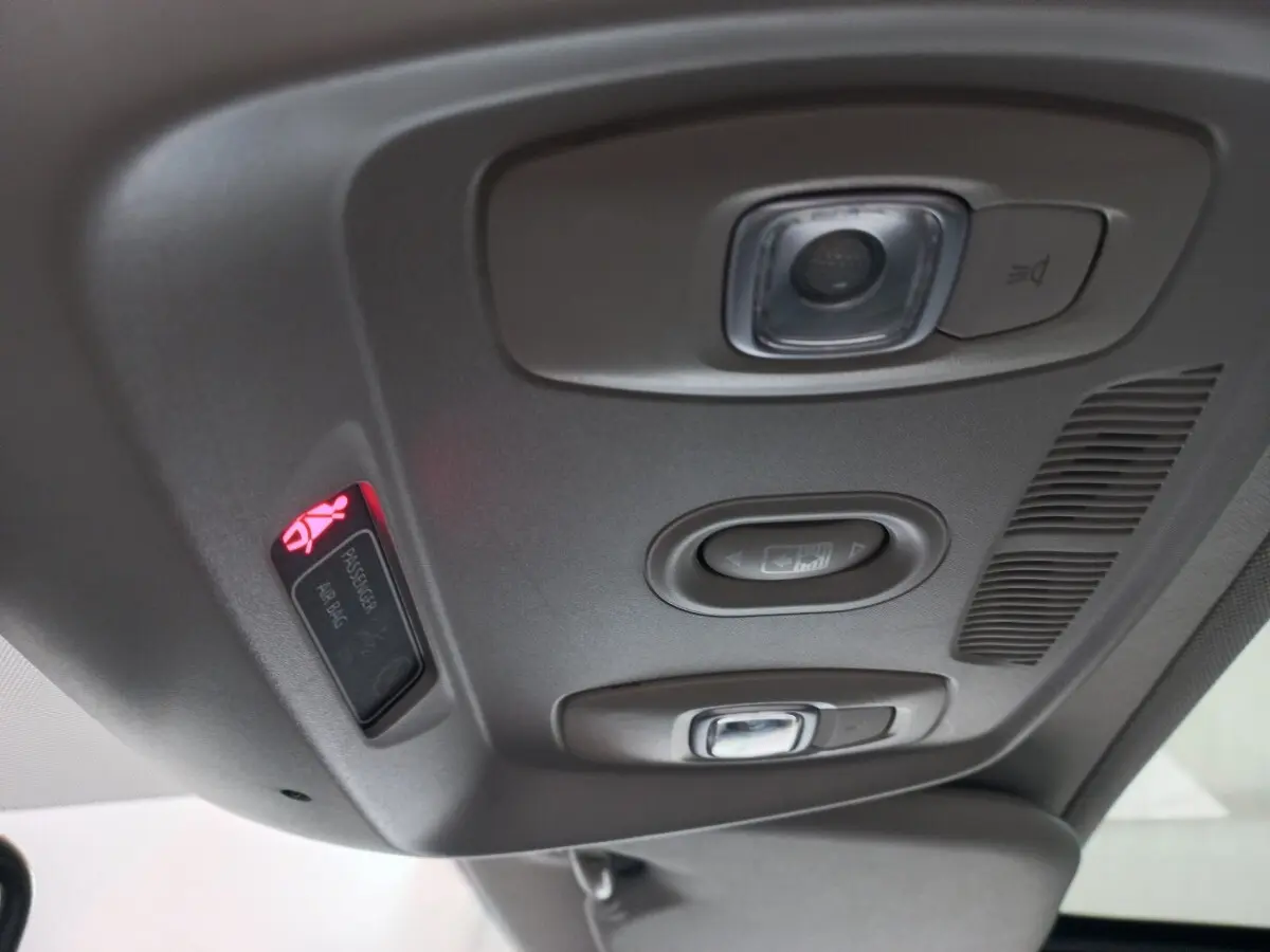 Vue en gros plan du plafonnier gris avec commandes d'éclairage et témoin airbag passager allumé dans un Renault Kadjar.