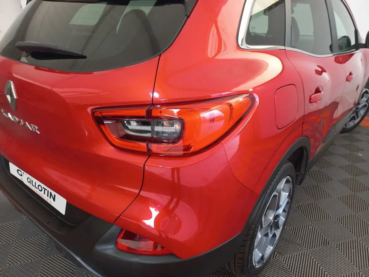 Vue 3/4 arrière droite du Renault Kadjar rouge brillant, avec feux arrière distinctifs et jantes alliage visibles.