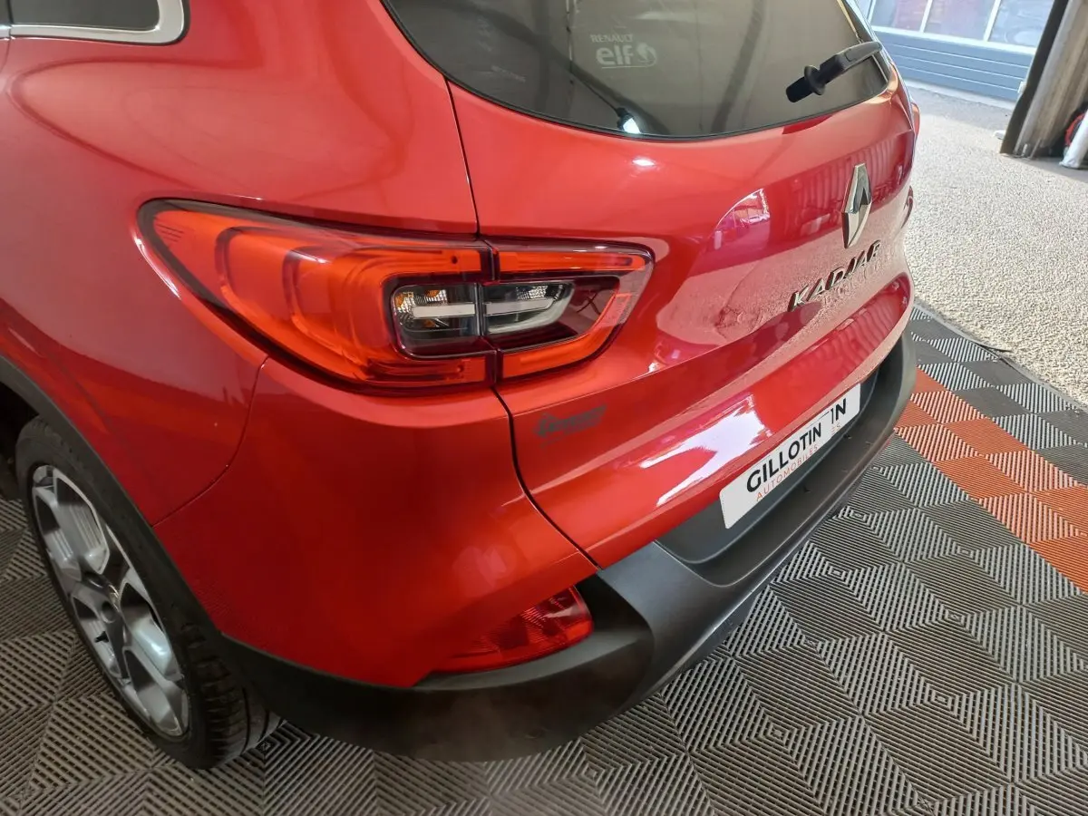 Vue 3/4 arrière droite d'un Renault Kadjar rouge avec feux arrière LED et logo visible sur un sol à motifs.