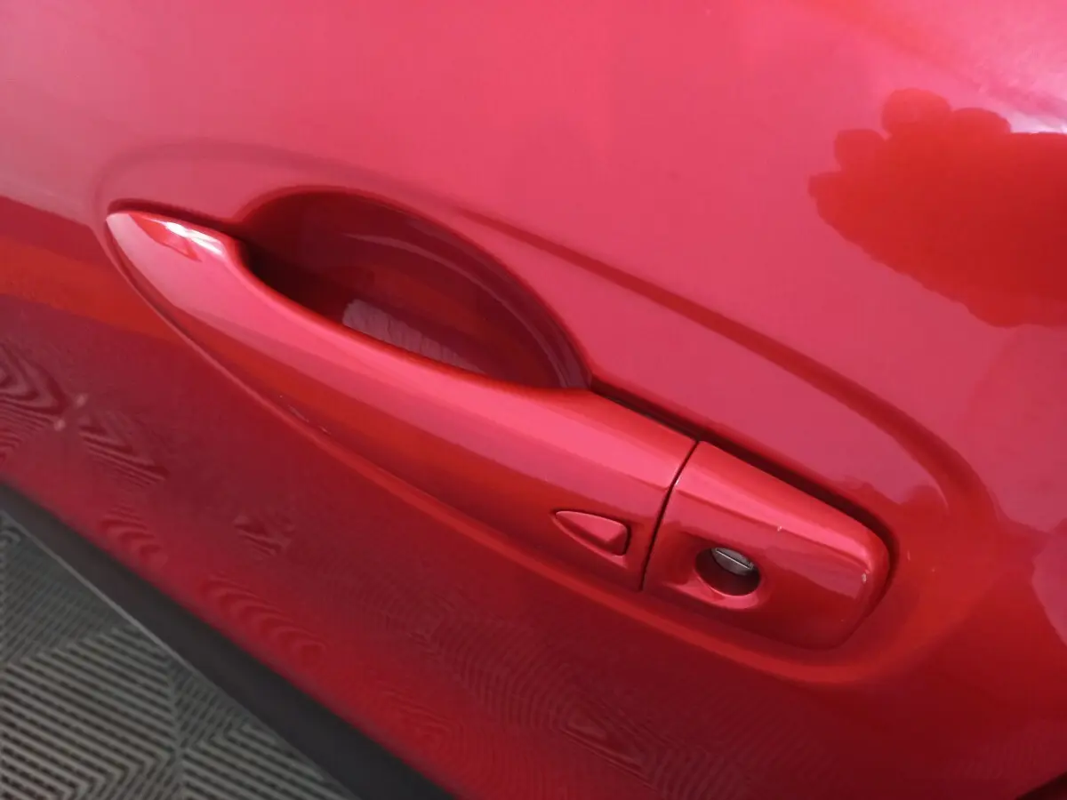 Poignée de porte côté gauche rouge vif du Renault Kadjar Intens Energy TCe 130 EDC, vue en gros plan.