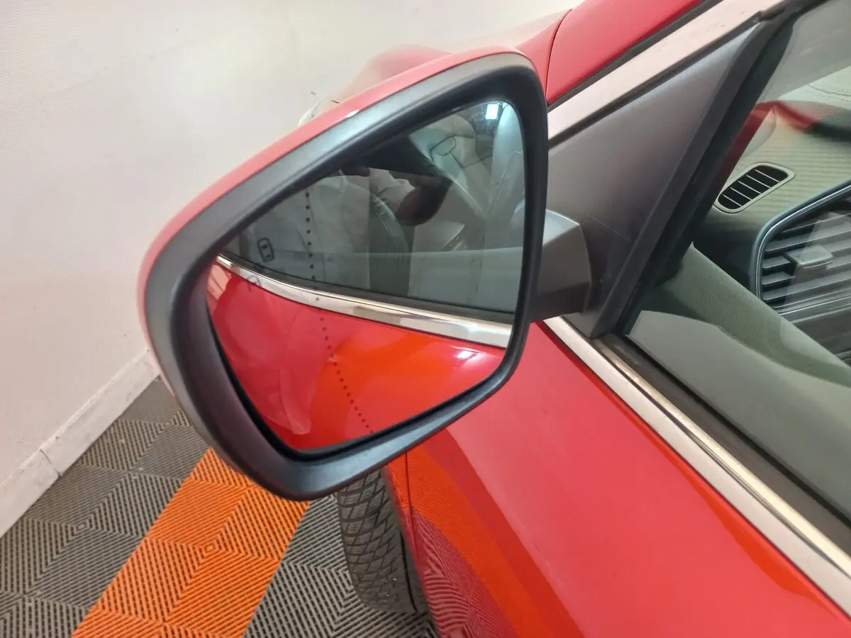 Rétroviseur côté gauche d’un Renault Kadjar rouge, vue rapprochée avec partie de la portière et intérieur visible.