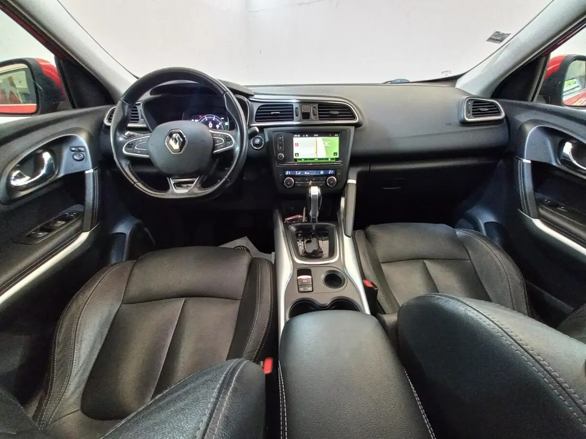 Vue intérieure avant du Renault Kadjar Intens, montrant tableau de bord noir avec écran tactile et sièges en cuir noir.