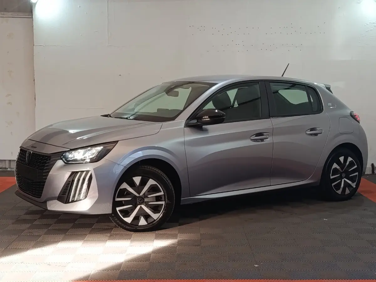 Peugeot 208 électrique gris clair vue de profil côté gauche, avec phares LED et jantes stylisées.
