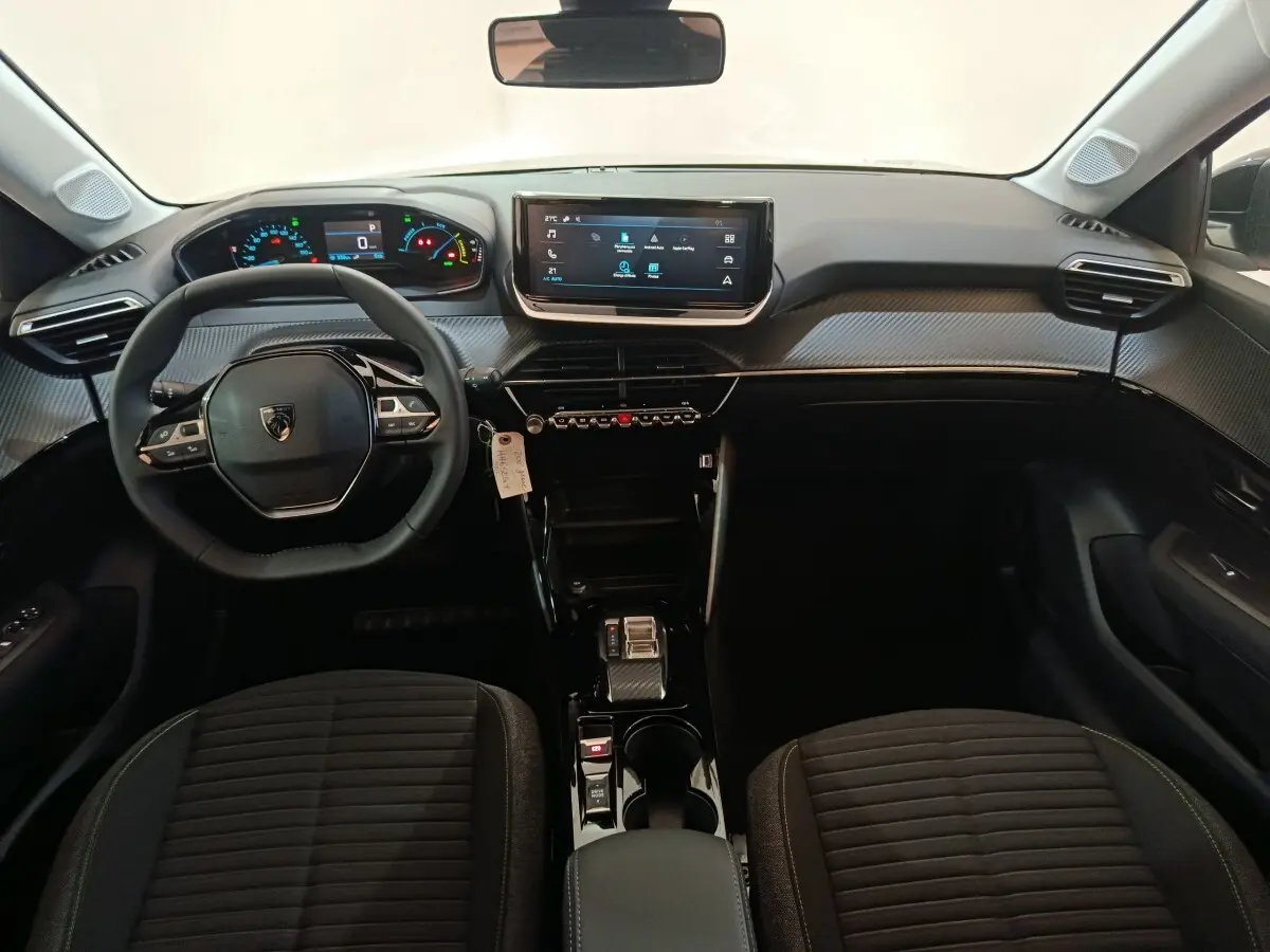 Vue intérieure avant de la Peugeot 208 électrique 2024, tableau de bord moderne avec écran tactile et volant multifonctions cuir.