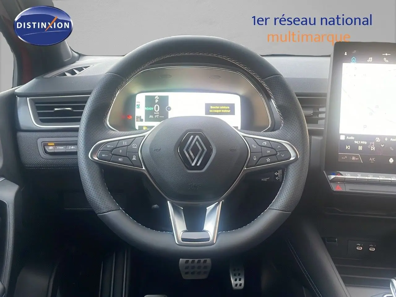 Vue frontale du volant noir perforé avec logo Renault, tableau de bord digital et écran tactile du Renault Captur E-Tech hybride 2025.