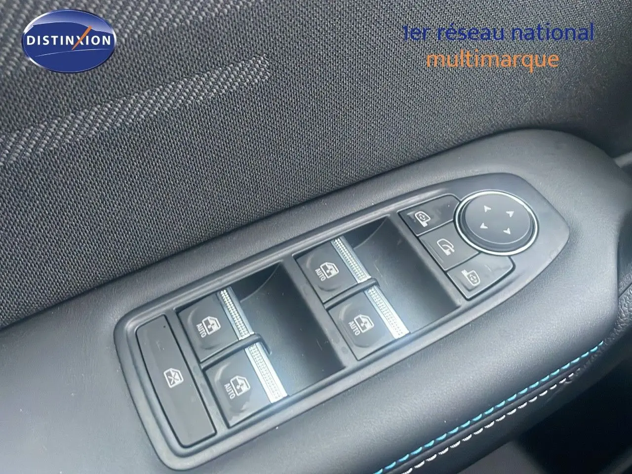 Gros plan sur les commandes des vitres électriques et rétroviseurs du côté gauche d’un Renault Captur rouge passion avec toit noir.