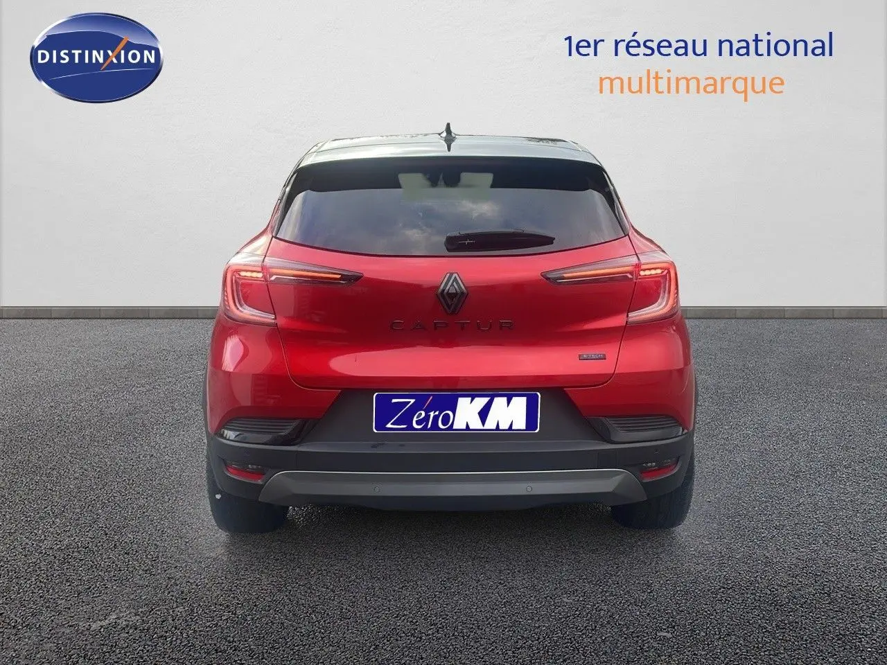 Vue arrière du Renault Captur E-Tech hybride rouge passion avec toit noir, feux LED allumés et plaque Zéro KM.