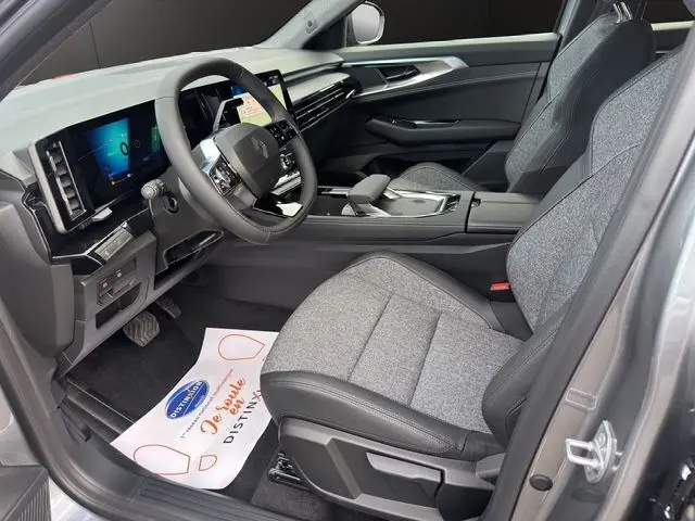 Intérieur avant droit du Renault Austral PH2 Techno hybride 2025, sièges tissu gris et tableau de bord moderne.