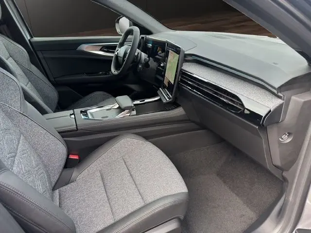 Intérieur avant droit du Renault Austral PH2 Techno hybride 2025, sièges gris et tableau de bord moderne avec écran tactile vertical.