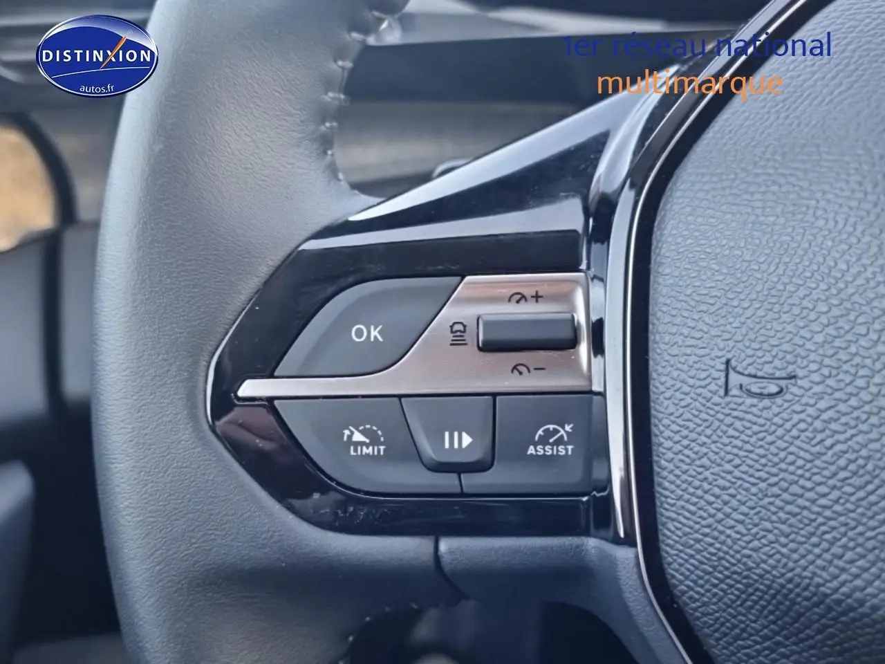 Gros plan sur les commandes gauche du volant cuir noir du Peugeot 408 gris sellenium e, avec boutons de régulateur et assistances.