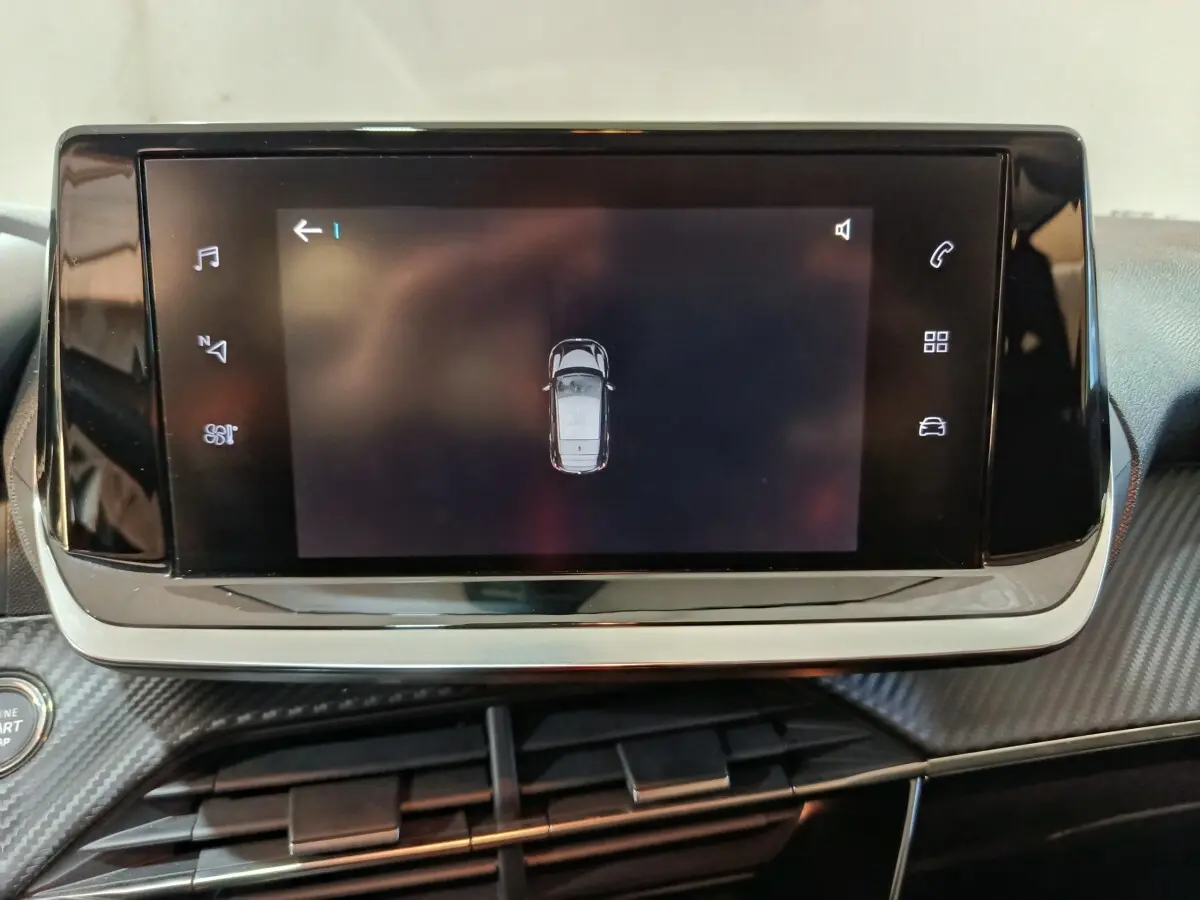 Écran tactile central affichant la vue aérienne du véhicule dans l’habitacle d’une Peugeot 208 Electrique blanche.