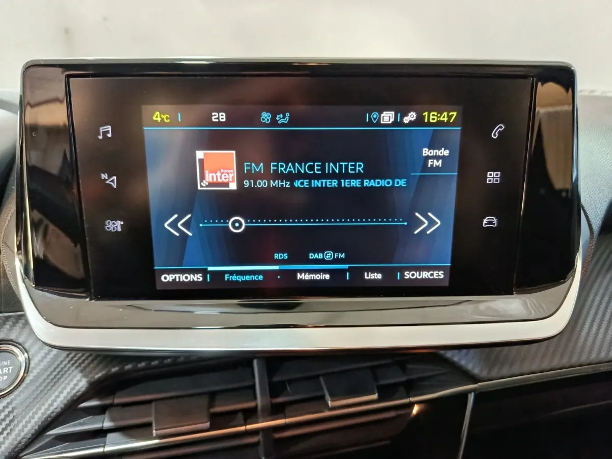 Écran tactile central du tableau de bord de la Peugeot 208 électrique Active Business, affichant la radio FM.