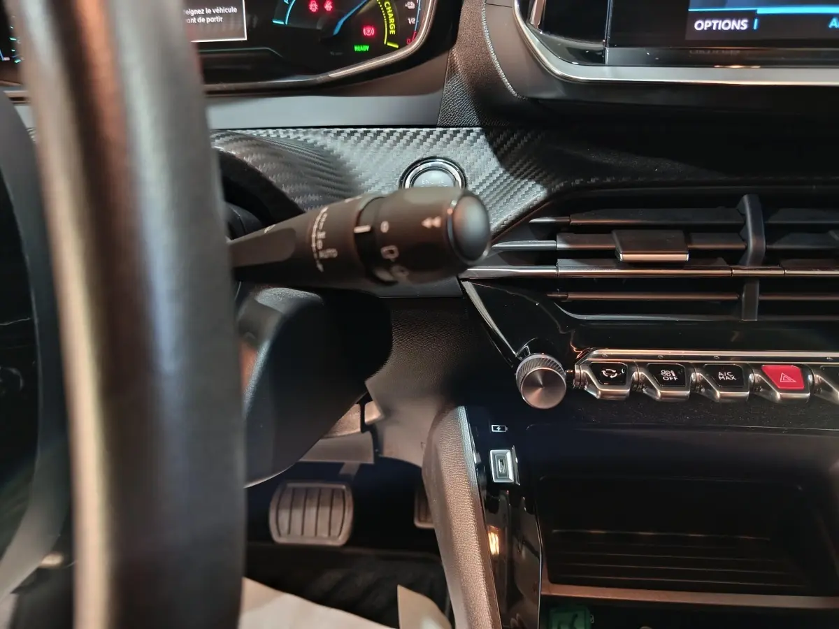 Vue intérieure rapprochée du tableau de bord et volant cuir noir du Peugeot 208 électrique Active Business 2020.