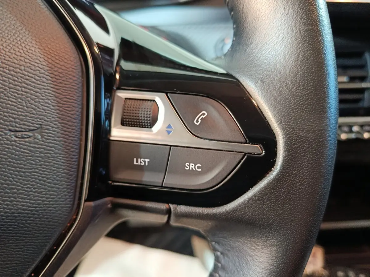 Gros plan sur le volant cuir noir de la Peugeot 208 électrique Active Business, avec commandes multifonctions visibles.