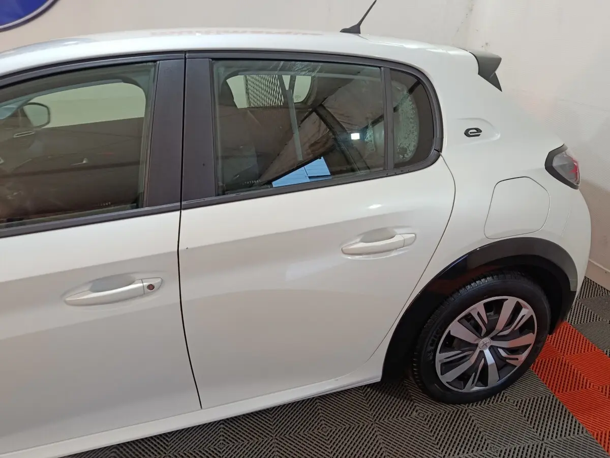 Vue latérale droite d'une Peugeot 208 électrique blanche avec logo "e" distinctif près de la porte arrière.