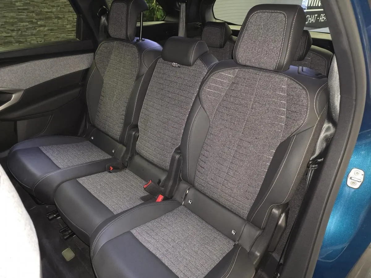 Vue intérieure côté gauche sur la banquette arrière tissu gris et cuir noir du Peugeot 5008 bleu 2025 hybride.